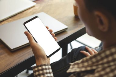 İş adamı kafedeki mesajınız için beyaz boş kopya alanı olan cep telefonu kullanıyor. Klasik ton. Seçmeli odak noktası