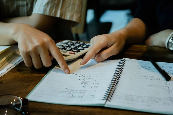 Asyalı genç erkek ve kadın oturmuş hesap makinesi eğitimi alıyor ve arkadaşlarıyla matematik kitapları kullanıyor. Genç öğrenci kampüsü, arkadaşa öğrenme konusunda yardımcı oluyor. Eğitim öğrenen insanlar