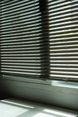 ev içi pencerenin dikey perdeleri kirli ve temiz yüzeylerin bir karışımını gösteriyor, dekorasyon tasarımı zorluklarını yansıtıyor odada farklı bir ruh hali ve ton yaratıyor