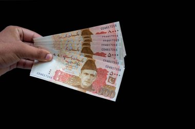Pakistan 5000 Note elinde, siyah arka planda izole edilmiş.