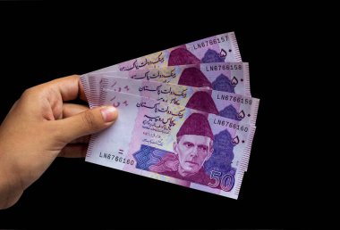 Pakistanlı 50 Not elinde, siyah arka planda izole edilmiş.