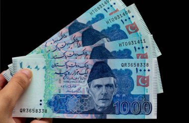 Pakistan 1000 Note elinde, siyah arka planda izole edilmiş.