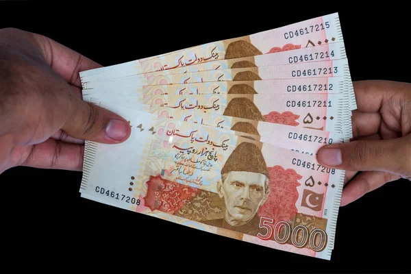 Pakistan 5000 Note elinde, siyah arka planda izole edilmiş.