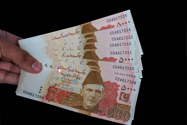 Pakistan 5000 Note elinde, siyah arka planda izole edilmiş.