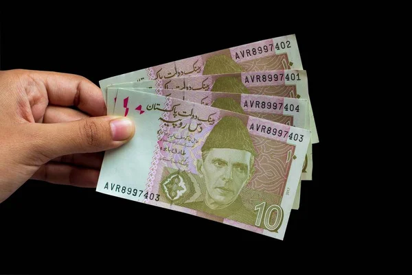 Pakistanlı 10 Not elinde, siyah arkaplanda izole edilmiş.