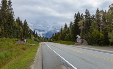 Yolun yanında sis ve Mount Robson Provincial Park işareti ile kaplı arka planda Mount Robson ile Canadian Rockies içine yol