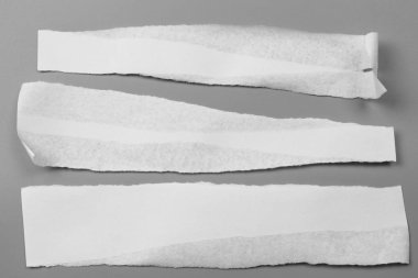 Gri arka planda beyaz yırtık kağıt. koleksiyon kağıdı yırtılması