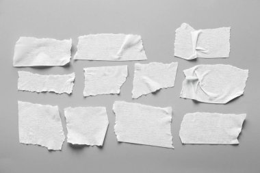 Gri arka plan üzerinde beyaz teyp kümesi. Yatay ve farklı boyut beyaz yapışkan bant, yapıştırıcı parçaları yırtılmış.