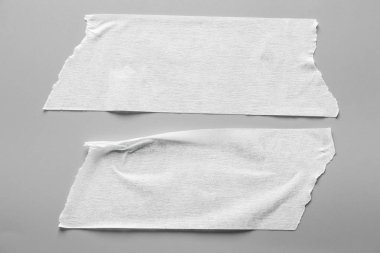 Gri arka plan üzerinde beyaz teyp kümesi. Yatay ve farklı boyut beyaz yapışkan bant, yapıştırıcı parçaları yırtılmış.