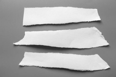 Gri arka planda beyaz yırtık kağıt. koleksiyon kağıdı yırtılması