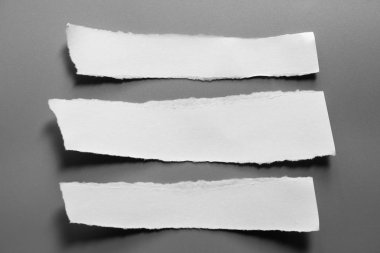 Gri arka planda beyaz yırtık kağıt. koleksiyon kağıdı yırtılması