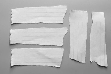 Gri arka planda beyaz yırtık kağıt. koleksiyon kağıdı yırtılması