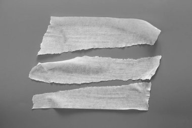 Gri arka plan üzerinde beyaz teyp kümesi. Yatay ve farklı boyut siyah bant, yapıştırıcı parçaları yırtılmış.