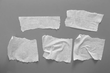 Gri arka plan üzerinde beyaz teyp kümesi. Yatay ve farklı boyut siyah bant, yapıştırıcı parçaları yırtılmış.