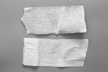 Gri arka plan üzerinde beyaz teyp kümesi. Yatay ve farklı boyut siyah bant, yapıştırıcı parçaları yırtılmış.