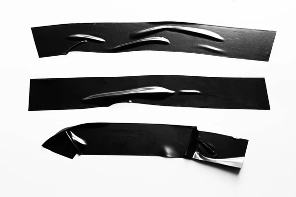 Set of black tapes on white background. Torn horizontal and different size black sticky tape, adhesive pieces.