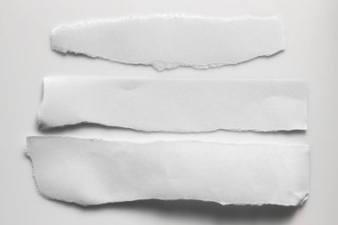Gri arka planda beyaz yırtık kağıt. koleksiyon kağıdı yırtılması
