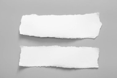 Gri arka planda beyaz yırtık kağıt. koleksiyon kağıdı yırtılması