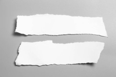 Gri arka planda beyaz yırtık kağıt. koleksiyon kağıdı yırtılması