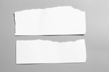 Gri arka planda beyaz yırtık kağıt. koleksiyon kağıdı yırtılması