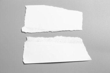 Gri arka planda beyaz yırtık kağıt. koleksiyon kağıdı yırtılması