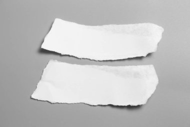Gri arka planda beyaz yırtık kağıt. koleksiyon kağıdı yırtılması