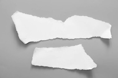 Gri arka planda beyaz yırtık kağıt. koleksiyon kağıdı yırtılması