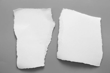 Gri arka planda beyaz yırtık kağıt. koleksiyon kağıdı yırtılması