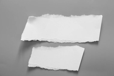 Gri arka planda beyaz yırtık kağıt. koleksiyon kağıdı yırtılması