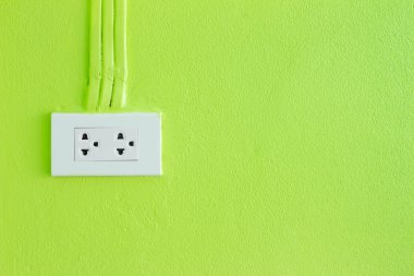 white socket on a wall with a green background.