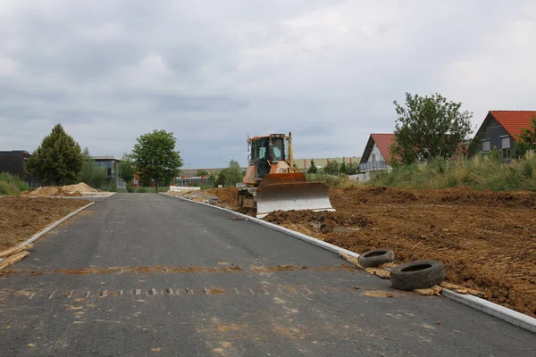 A road has been built and utility line have been laid for the construction of a new residential community in Germany.The bulldozer prepares the soil for the construction of houses