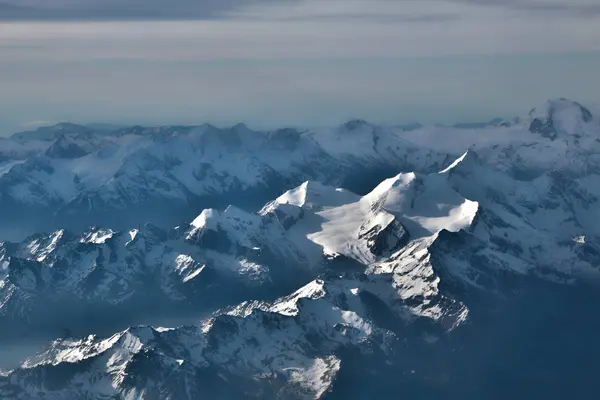 The snow-covered peaks of the mountains from the aircraft. — Stock Photo, Image