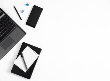Minimalist geometri ofisi düzlüğü. Dizüstü bilgisayar, kalem, not defteri, beyaz arkaplan üzerinde kopya alanı olan telefon. 