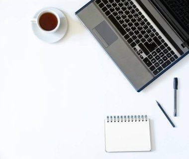 Minimalist geometri ofisi düzlüğü. Dizüstü bilgisayar, not defteri, beyaz arka planda bir fincan çay, fotokopi alanı. 