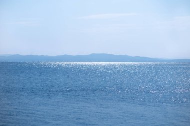 Mavi gölde dalgalar. Dağlar uzaktan görülebilir. Rahatlama ve dinginlik kavramı