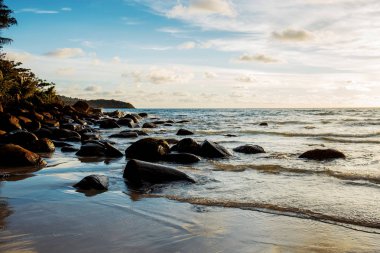 Kayaların üzerinde gökyüzü günbatımı kum plaj.