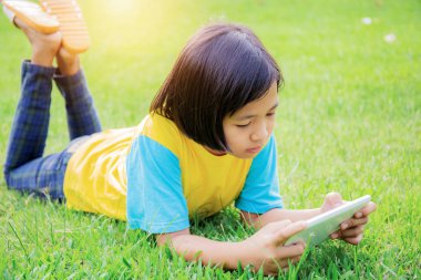 Asyalı kız Park'ın bahçesinde tablet kullanarak.