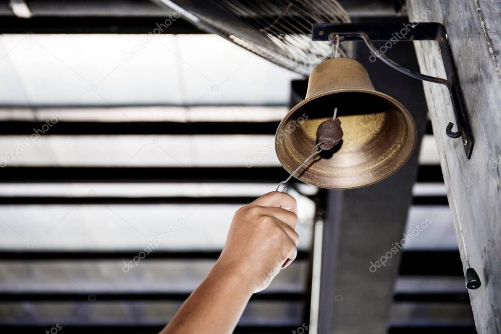 Hand is shaking bell hanging on pole of the boxing stadium.