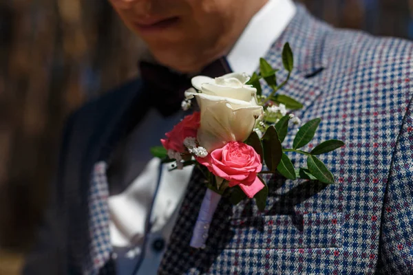 Elements of the groom\'s clothes on the wedding day. Blue butterfly, tuxedo and boutonniere with white roses.