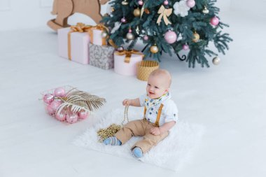 Küçük çocuk Noel ağacı arka plan üzerinde oturan.