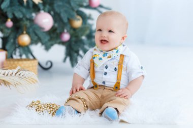 Küçük çocuk Noel ağacı arka plan üzerinde oturan.
