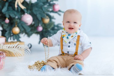 Küçük çocuk Noel ağacı arka plan üzerinde oturan.