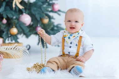 Küçük çocuk Noel ağacı arka plan üzerinde oturan.