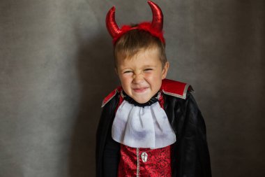 Gri arka planda cadılar bayramı vampir kostümü giyen küçük çocuk. 