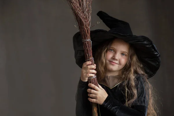 Šťastná dívka v halloween čarodějnice kostým na šedém pozadí — Stock fotografie