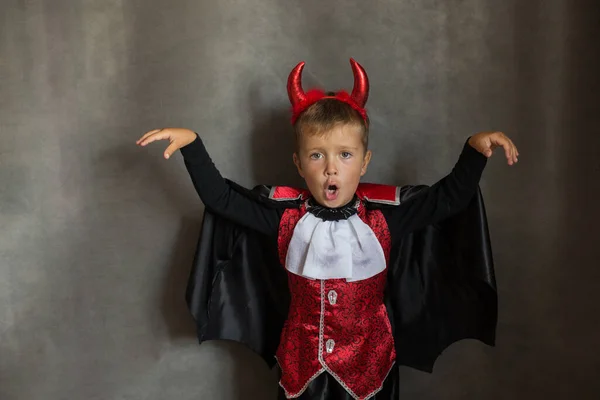 Malý chlapec v halloween upíří kostým na šedém pozadí. Emoční dítě. — Stock fotografie
