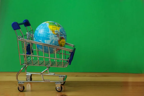 Pequeño planeta terrestre en el carrito de compras. Concepto de venta. — Foto de Stock