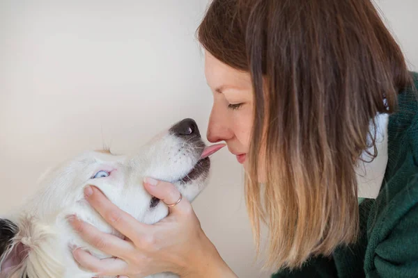 European woman in green jacket kissing Australian shepherd — Stock Photo, Image