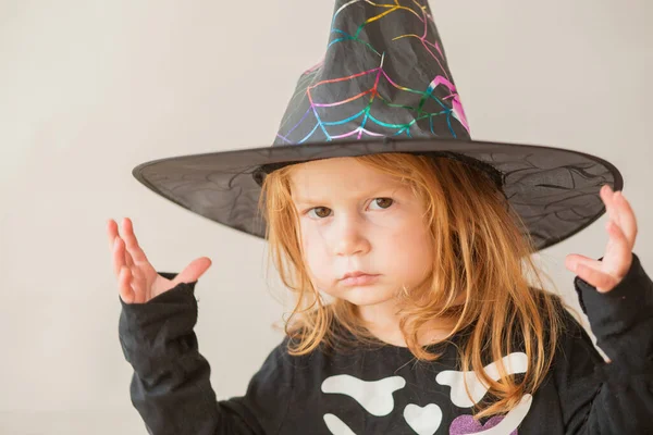 Emocionální batole dívka v halloween čarodějnice kostým na šedém pozadí — Stock fotografie