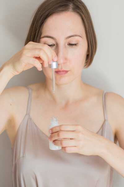 Close up beauty portrait of woman holding bottle of serum